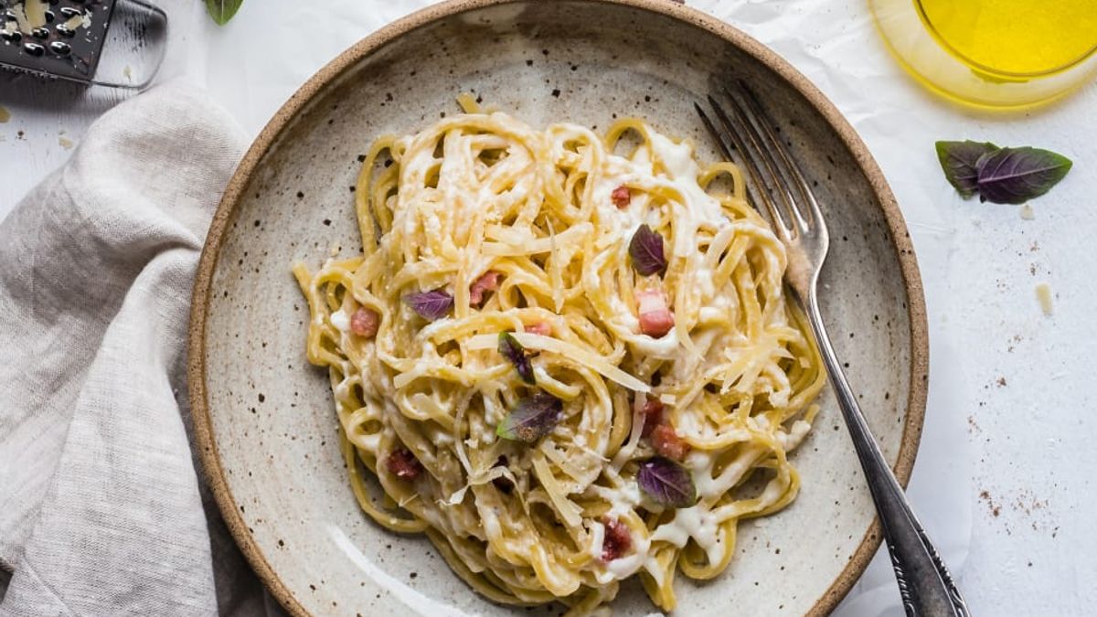 Een rustiek bord met spaghetti carbonara op een mooi opgemaakte tafel