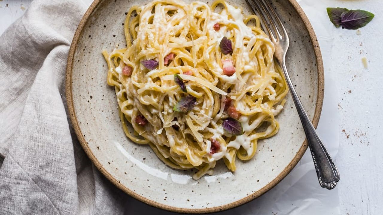 Een rustiek bord met spaghetti carbonara op een mooi opgemaakte tafel